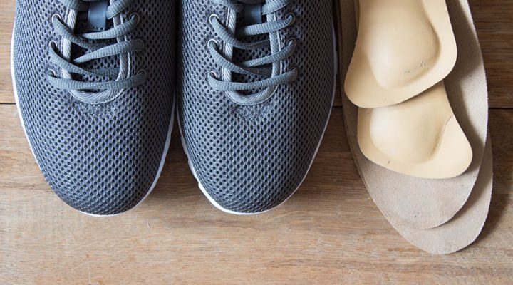 Custom Orthotics Oakville, two grey shoes with laces with 2 pairs of custom orthotics