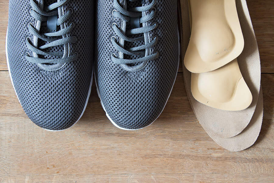 Custom Orthotics Oakville, two grey shoes with laces with 2 pairs of custom orthotics
