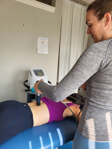 A female patient receiving shockwave therapy for lower back pain