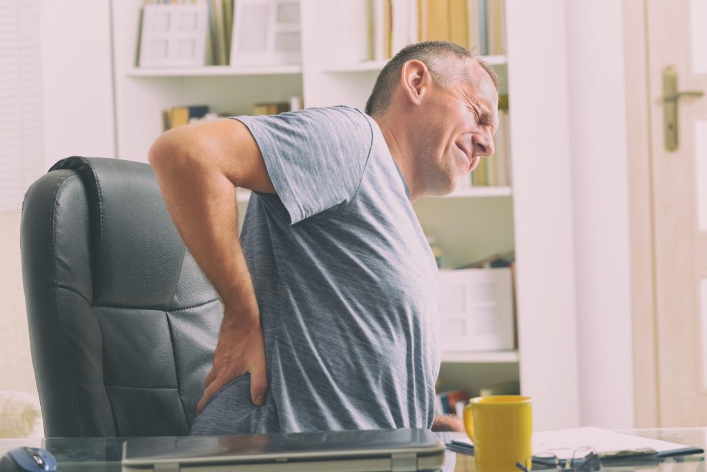 Man experiencing lower back pain while sitting at home
