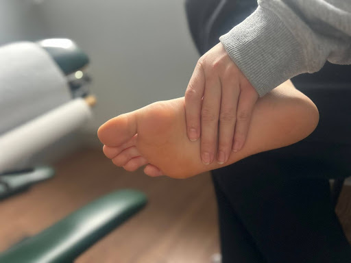 Person holding the arch of their foot, indicating foot or arch pain.