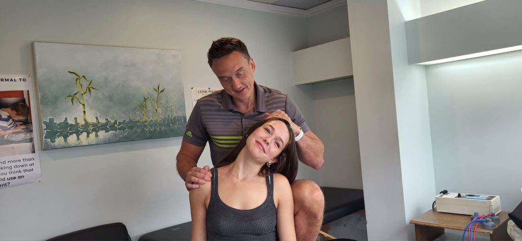 Dr. Steve performing hands on soft tissue release for TOS of a females patients neck, his thumb is pressing on the space between her neck muscles and colar bone