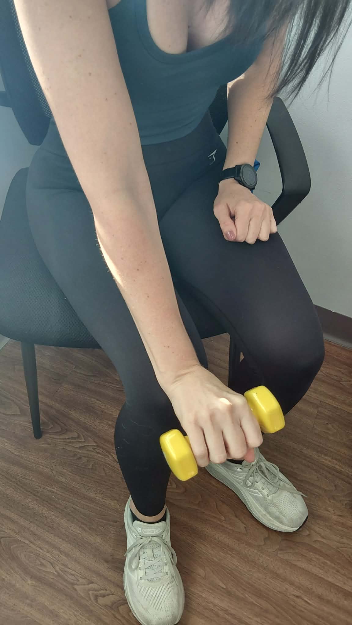 female patient holding a 3lbs yellow weight