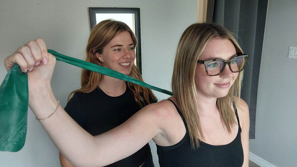 a female sports physiotherapist working with bands and a female patients shoulder
